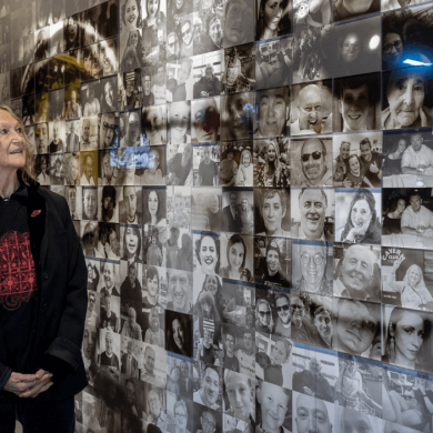 Julia Baird stood infront of a large wall with a portrait of John Lennon on.