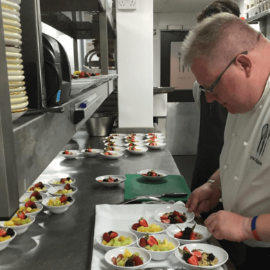 Chef Paul Askew in the kitchen plating up food.