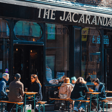 outside of The Jacaranda pub with people sitting on benches