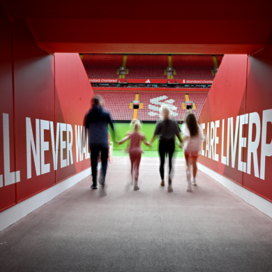 A family of four walking out of the tunnel and towards the pitch at Anfield Stadium
