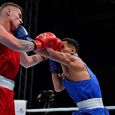 Two boxers in a ring, one wearing red and one wearing blue fighting.