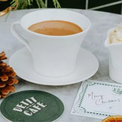 Petit cafe table with a mug of hot chocolate and cup of whipped cream.