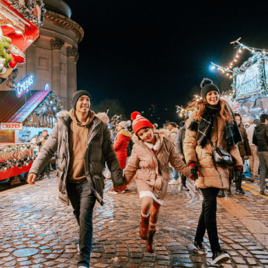 A family of three with two adults and a child at the Liverpool Christmas markets.