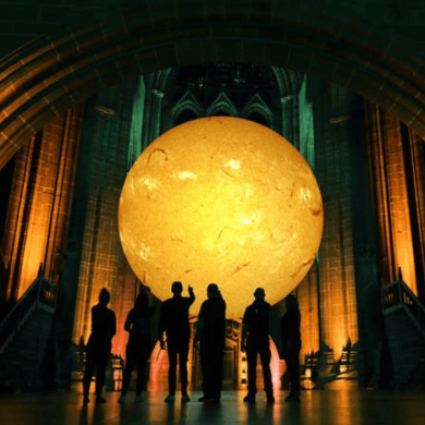 An installation of a giant sun hanging inside a cathedral.