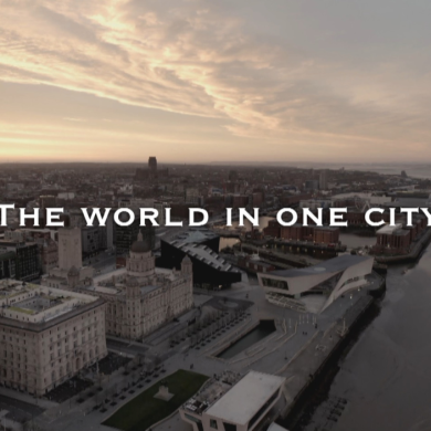A drone shot of Liverpool's Pier Head at sunrise with the words The World in One City over the top.