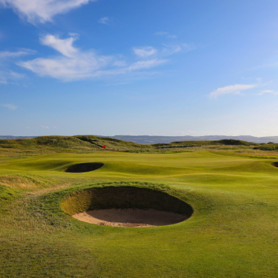 A bunker on a golf course in Wirral on lush green grass with a blue sky