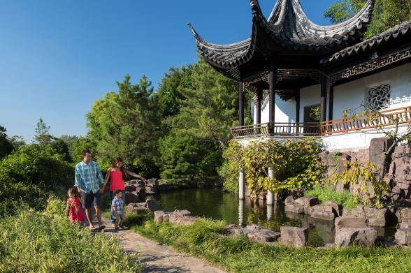 Snug Harbor Cultural Center & Gardens Exterior of a family walking by a building surrounded by green vegetation at the New York Chinese Scholar's Garden at Snug Harbor