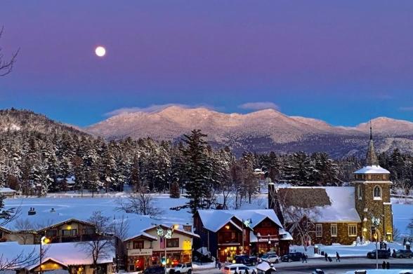Lake Placid, winter Aerial view of shops and a church in Lake Placid covered in snow with the Adirondack Mountains in the distance
