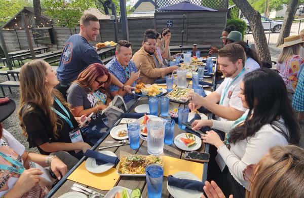 Group of Young professionals dining on the patio at The Yard as server puts food on the table