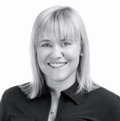 Black and white photo of a smiling woman in a button up dark shirt