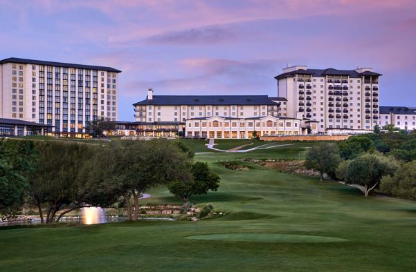 Lush green golf course leading up to Omni Barton Creek Hotel