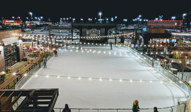 About a dozen people enjoying a nighttime skating session at an outdoor rink in Wichita, KS