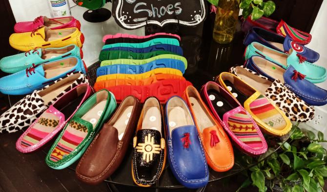 Colorful slip-on shoes arranged in a circle around the outside of a circular glass table