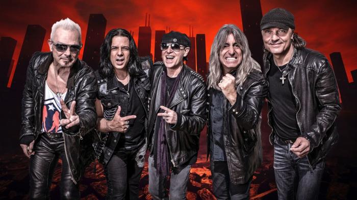 Five members of rock and roll band, The Scorpions, pose in front of cityscape with red hue