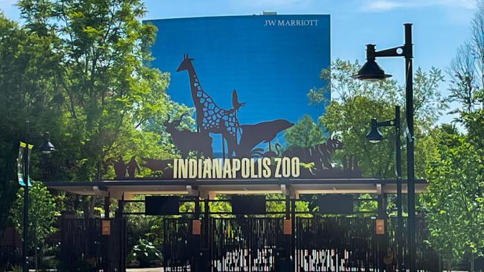 The entrance to the Indianapolis Zoo. Signage shows silhouettes of animals with the words "Indianapolis Zoo" underneath.