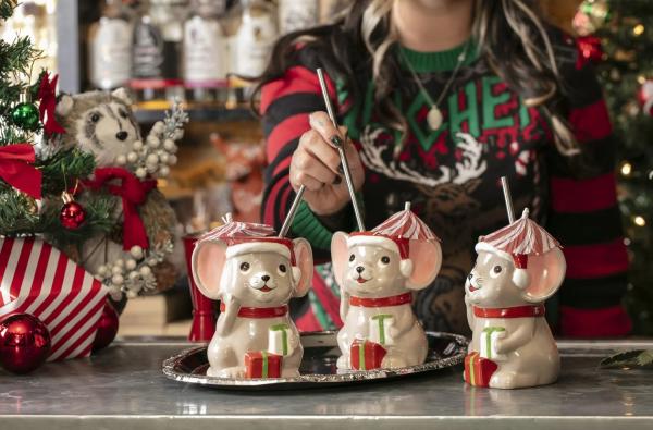 Festive holiday cocktails served in three ceramic mouse-shaped mugs with Santa hats and striped umbrellas, displayed on a tray at the Miracle Christmas Pop-Up Bar in Dublin, Ohio, with Christmas decorations in the background.