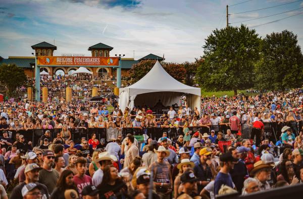 A colorful crowd of people gather at the annual Peacemaker Music Festival in Fort Smith's Riverfront Park.