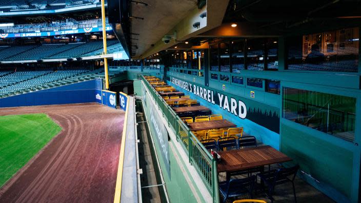 View of Leinenkugel’s Barrel Yard inside American Family Field. The photo shows rows of outdoor tables and chairs overlooking left field, with the ballpark’s green walls and signage prominently featuring the Barrel Yard name.