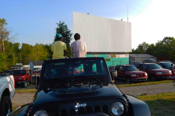 Teenagers sit on their car waiting for the drive-in movie at Georgetown Drive-In