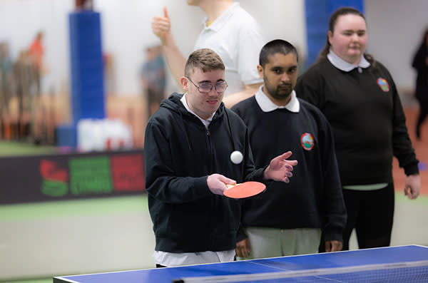 A young man trying out a table tennis bat and ball.