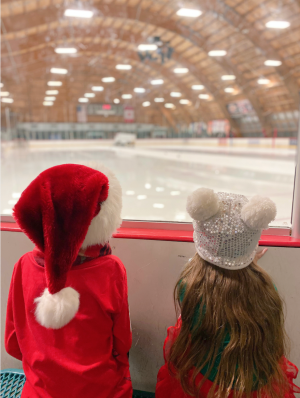 Image of two kids in Christmas hats overlooking an ice skating rink.