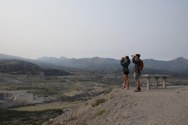 Man and woman look through binoculars at top of Mount St. Helens