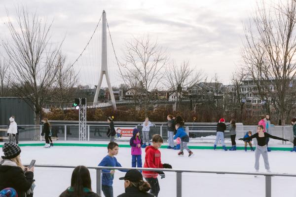 Families ice skating on the ice rink at Riverside Crossing Park