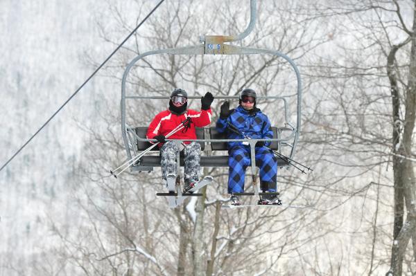 Two skiers at Bristol Mountain waiving on the lift