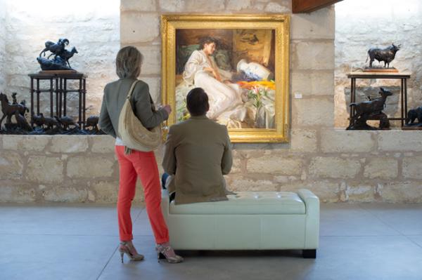 two individuals observing a painting at an art gallery
