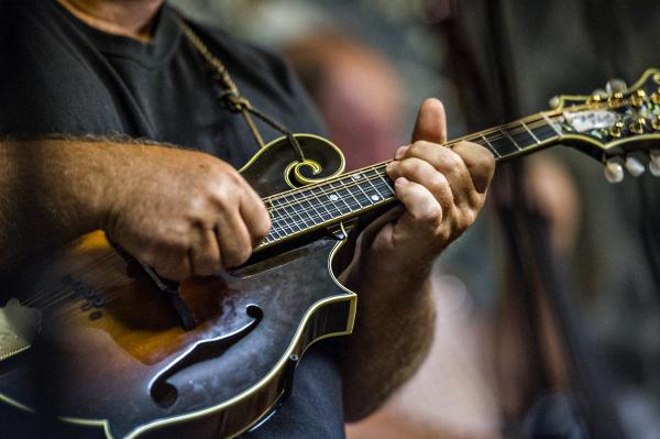 close up man playing a black violin like a guitar