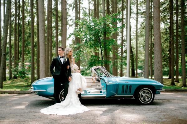 bride and groom in front of car