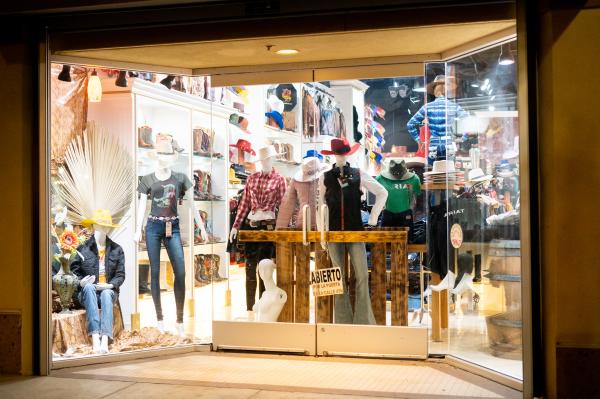 Front display of RR Western Wear in Santa Ana, showcasing mannequins dressed in Western-inspired apparel, including cowboy hats, boots, and plaid shirts, with shelves of additional merchandise in the background.
