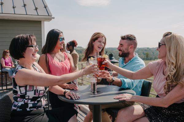 Group of four women and one man having drinks together at an outdoor table