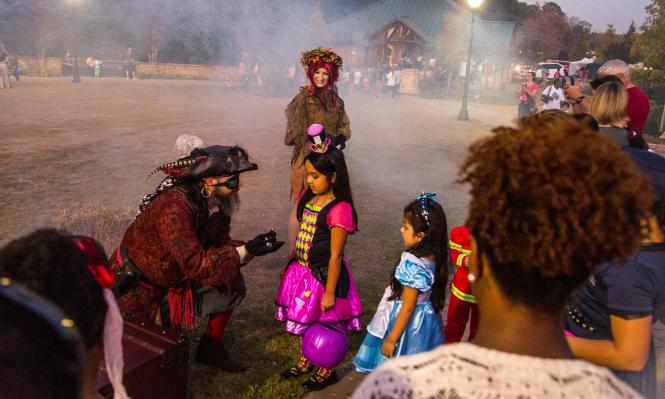 Pirate passing out candy to young trick-or-treaters at Spooky Springs in Sandy Springs