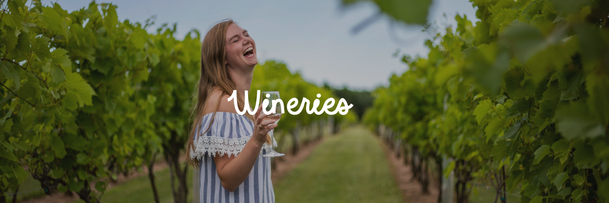 Girl sipping wine and walking down the aisles of a vineyard with the word "wineries" on top of the image