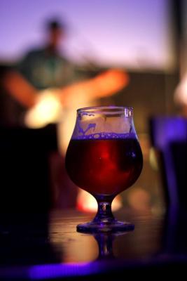 image of a beer with performing on stage in the background out of focus.