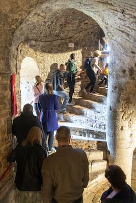 A queue of people stretches up a stone spiral staircase