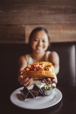 a very happy girl holding up a lobster roll at Rockfish Public House