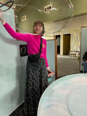 A young woman plays with the giant bubbles at Explora