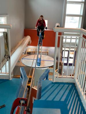 A young woman rides the high wire bike at Explora