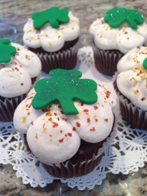 Guinness flavored cupcake with white icing and a green shamrock on top from Our Cupcakery.