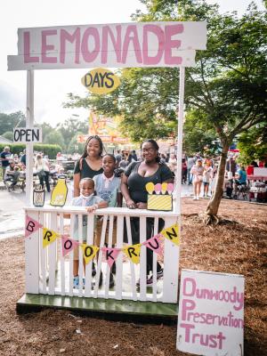 Smiling mother & kids at lemonade booth posing for a photo