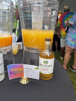 A display showing a bottle of Mutiny rum in next to a sign that reads "Island Mule".  Both are sitting in front of a mixer filled with an orange-colored drink.