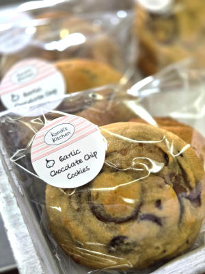 A tray of wrapped cookies that have a sticker saying "Kandi's Kitchen. Garlic Chocolate Chip Cookies"