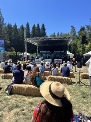 People sit on hay bails to watch Cooking Demos on the main stage