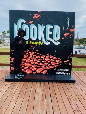 a black mural with words the words "hooked on Gulf County." The mural also has fish swimming on it.