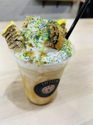 king cake flavored latte topped with whipped cream, sprinkles, and king cake bits