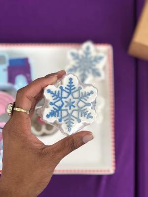A hand holding a "bath bomb", a small, white/blue, snowflake-shaped soap for bubble baths.