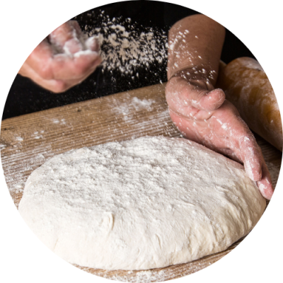 Hands spreading flour on dough