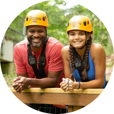 Father and daughter smiling in ziplining gear